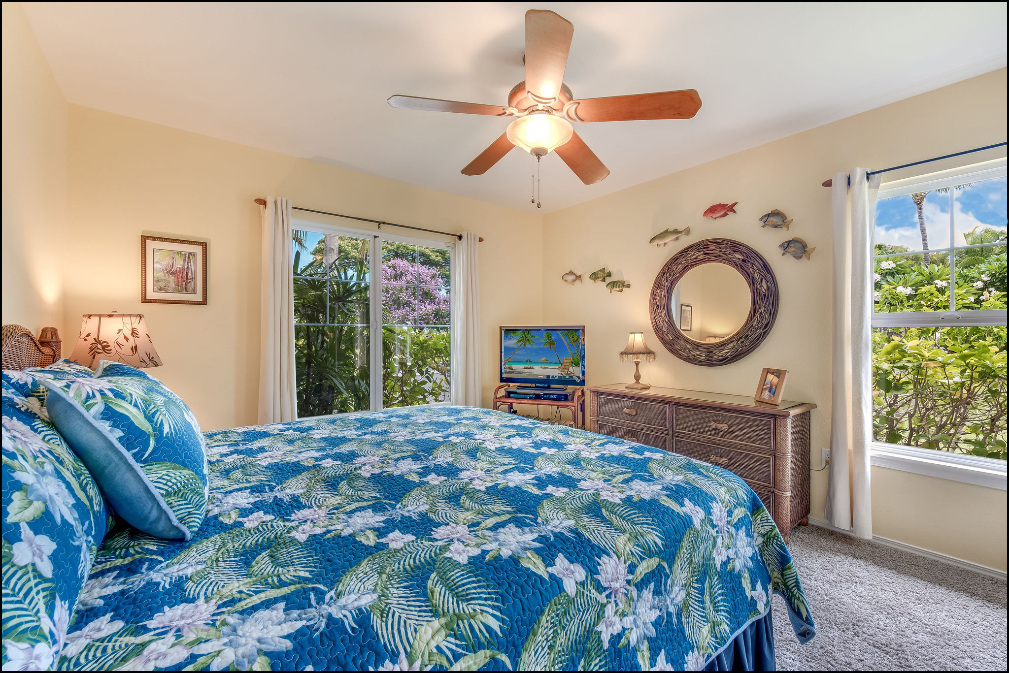 Ground floor second bedroom with windows on two sides has bright Hawaiian decor plus TV, DVD player and ceiling fan